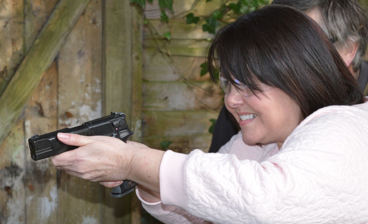 Aiming with a pistol while grinning